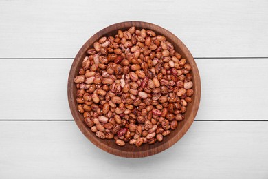 Bowl with dry kidney beans on white wooden table, top view