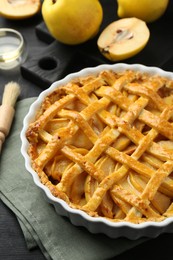 Photo of Tasty homemade quince pie and fresh fruits on black wooden table, closeup