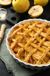 Tasty homemade quince pie and fresh fruits on black wooden table, closeup