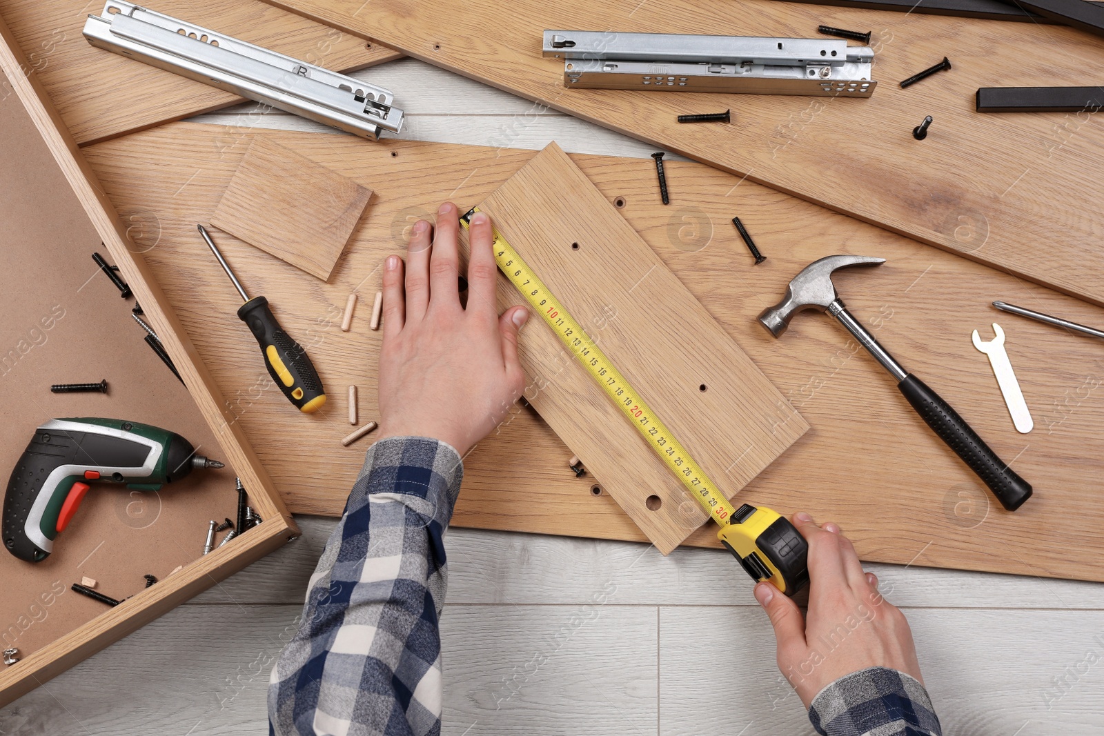 Photo of Man assembling wooden furniture on floor, top view