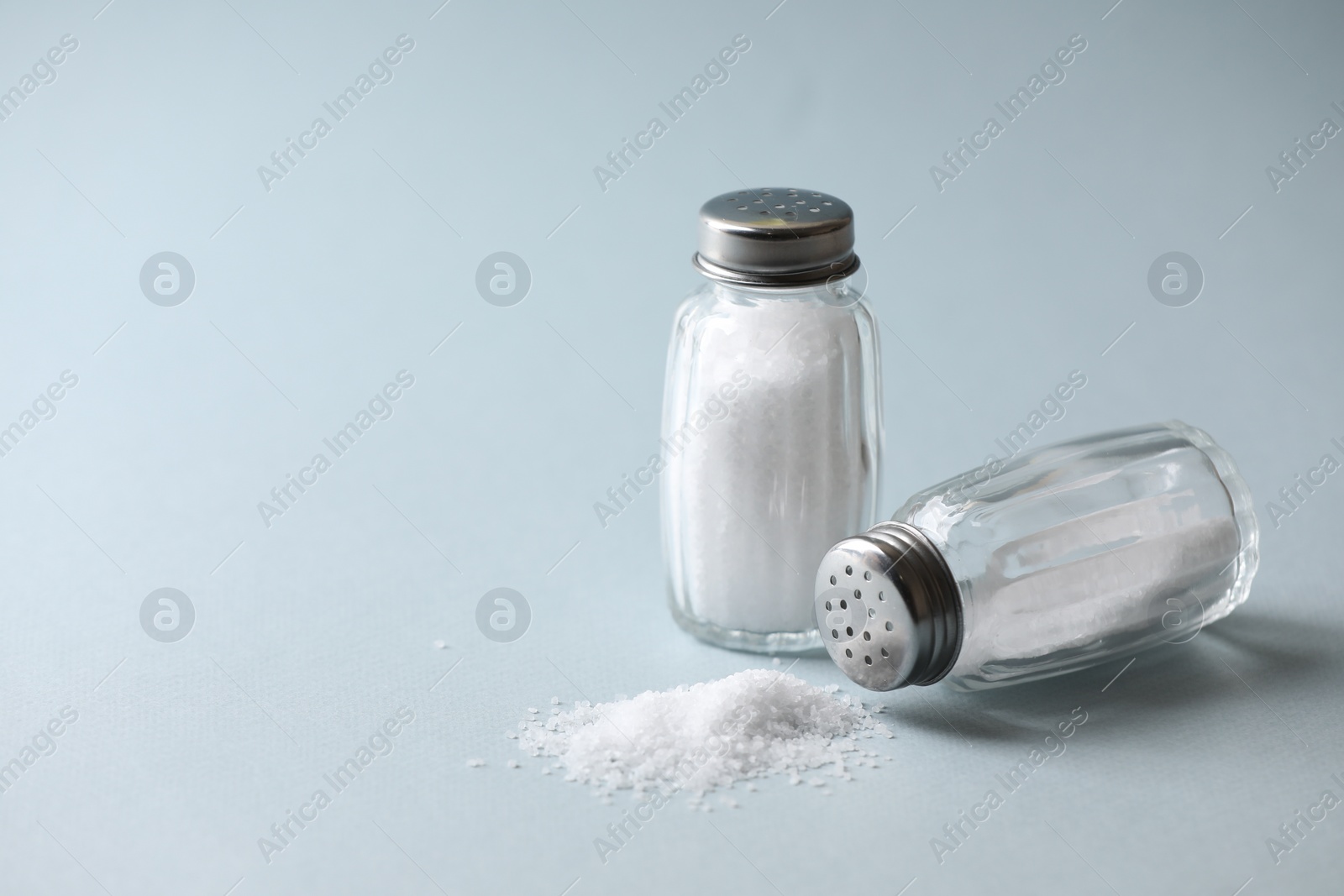 Photo of Natural salt in shakers on color background, space for text