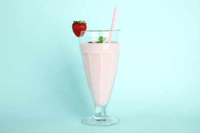 Photo of Tasty fresh milk shake with strawberry on light blue background