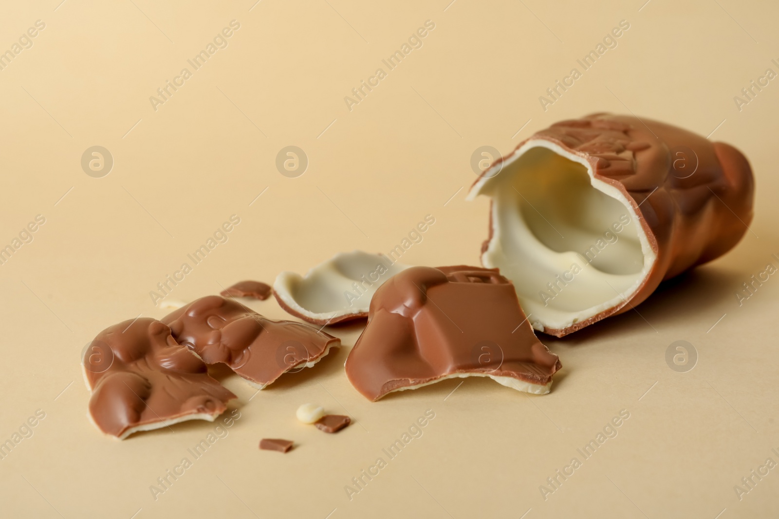 Photo of Broken chocolate Santa Claus on beige background. Space for text