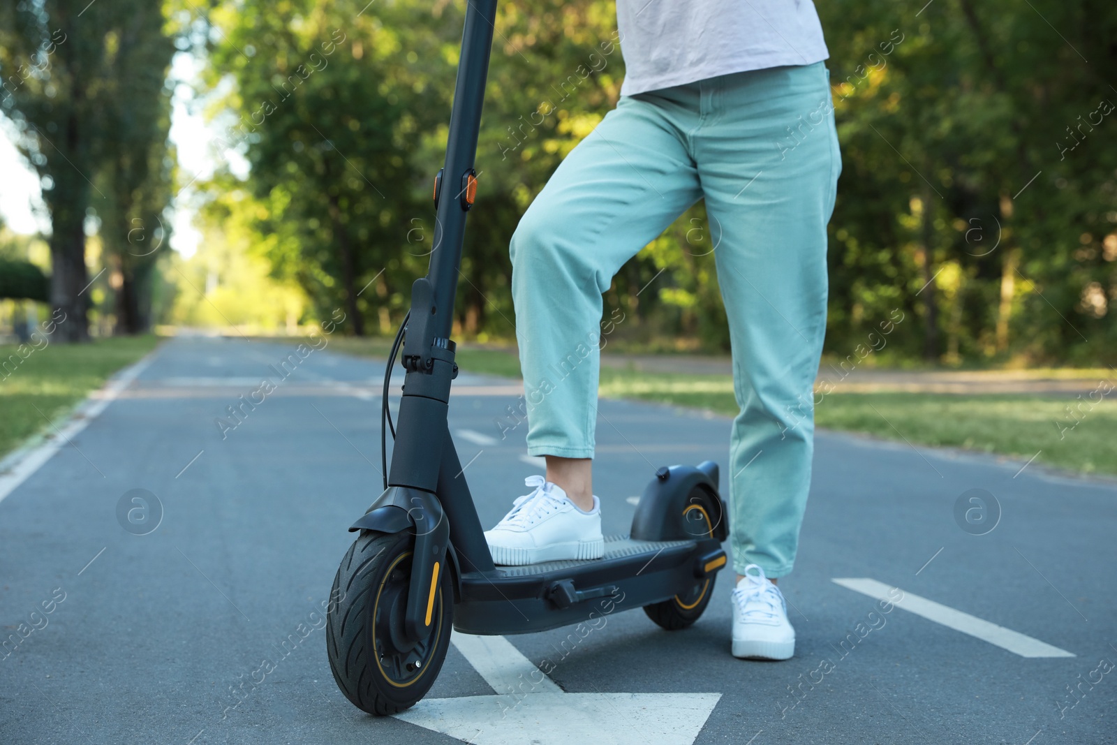 Photo of Woman with modern electric kick scooter in park, closeup