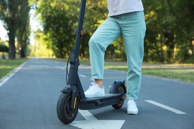 Photo of Woman with modern electric kick scooter in park, closeup