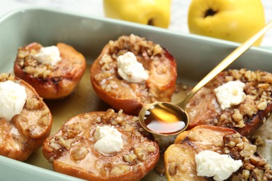 Photo of Tasty baked quinces with nuts, honey and cream cheese in dish, closeup