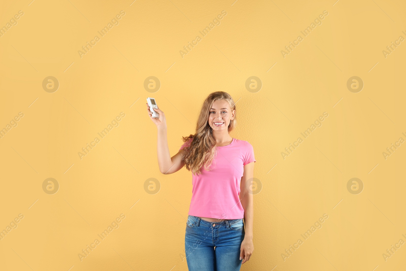 Photo of Young woman with air conditioner remote on color background