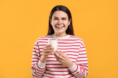 Photo of Happy woman with milk mustache holding glass of tasty dairy drink on yellow background