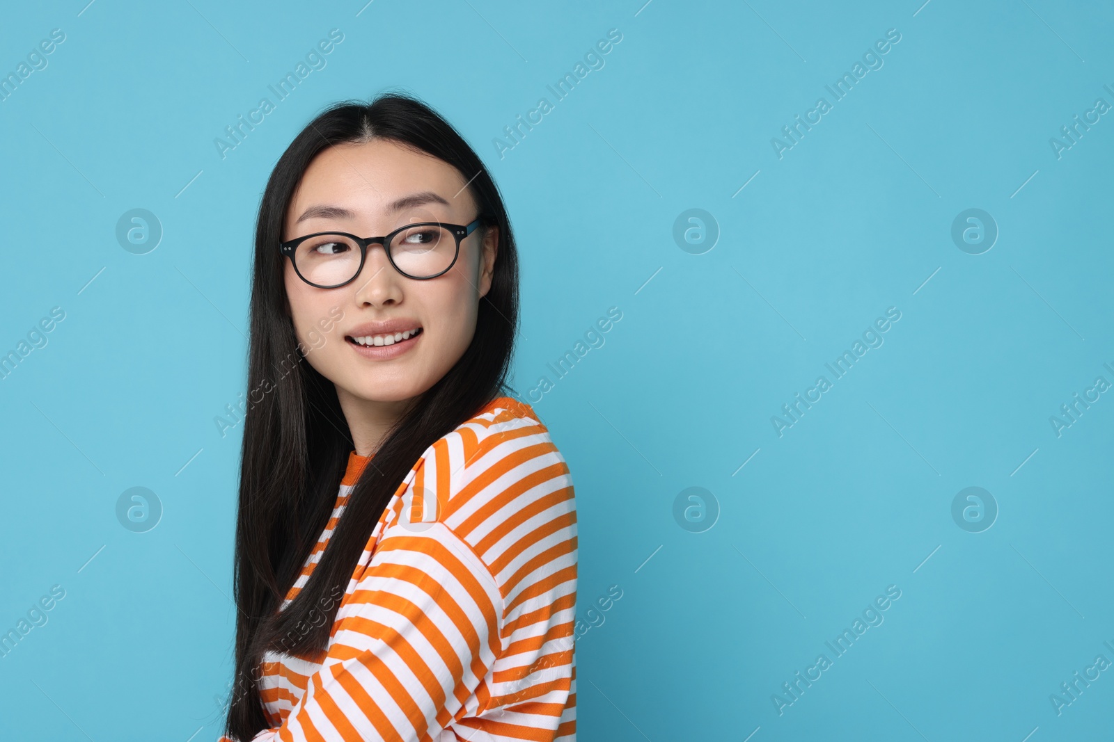 Photo of Portrait of happy woman in glasses on light blue background. Space for text