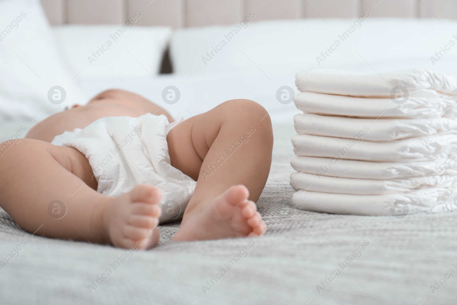 Photo of Cute little baby in diaper on bed at home