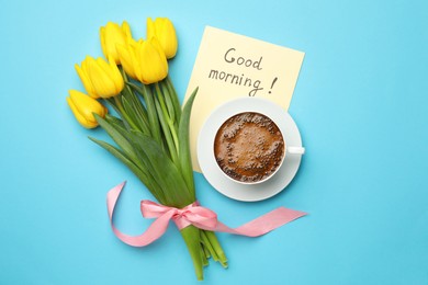 Photo of Cup of aromatic coffee, beautiful yellow tulips and Good Morning note on light blue background, flat lay