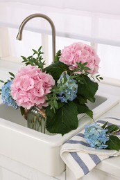 Vase with beautiful hortensia flowers in kitchen sink