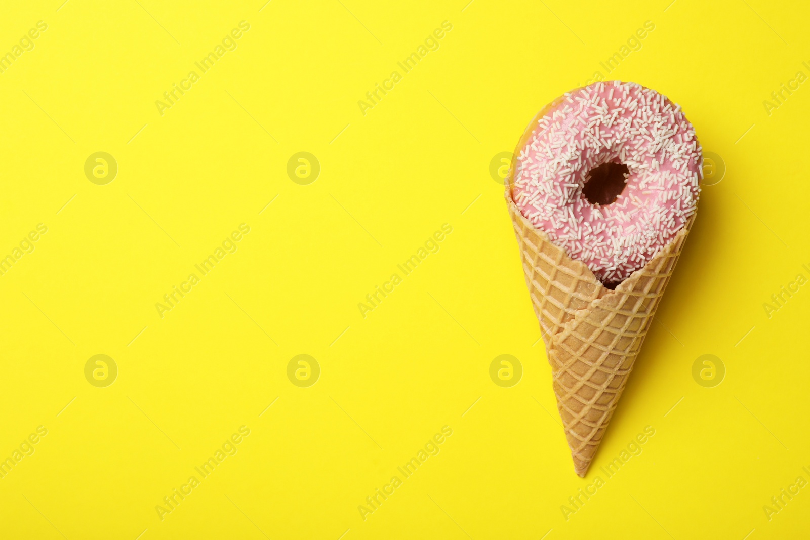 Photo of Ice cream made with donut on yellow background, top view. Space for text