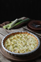 Photo of Tasty leek pie and raw stems on old wooden table