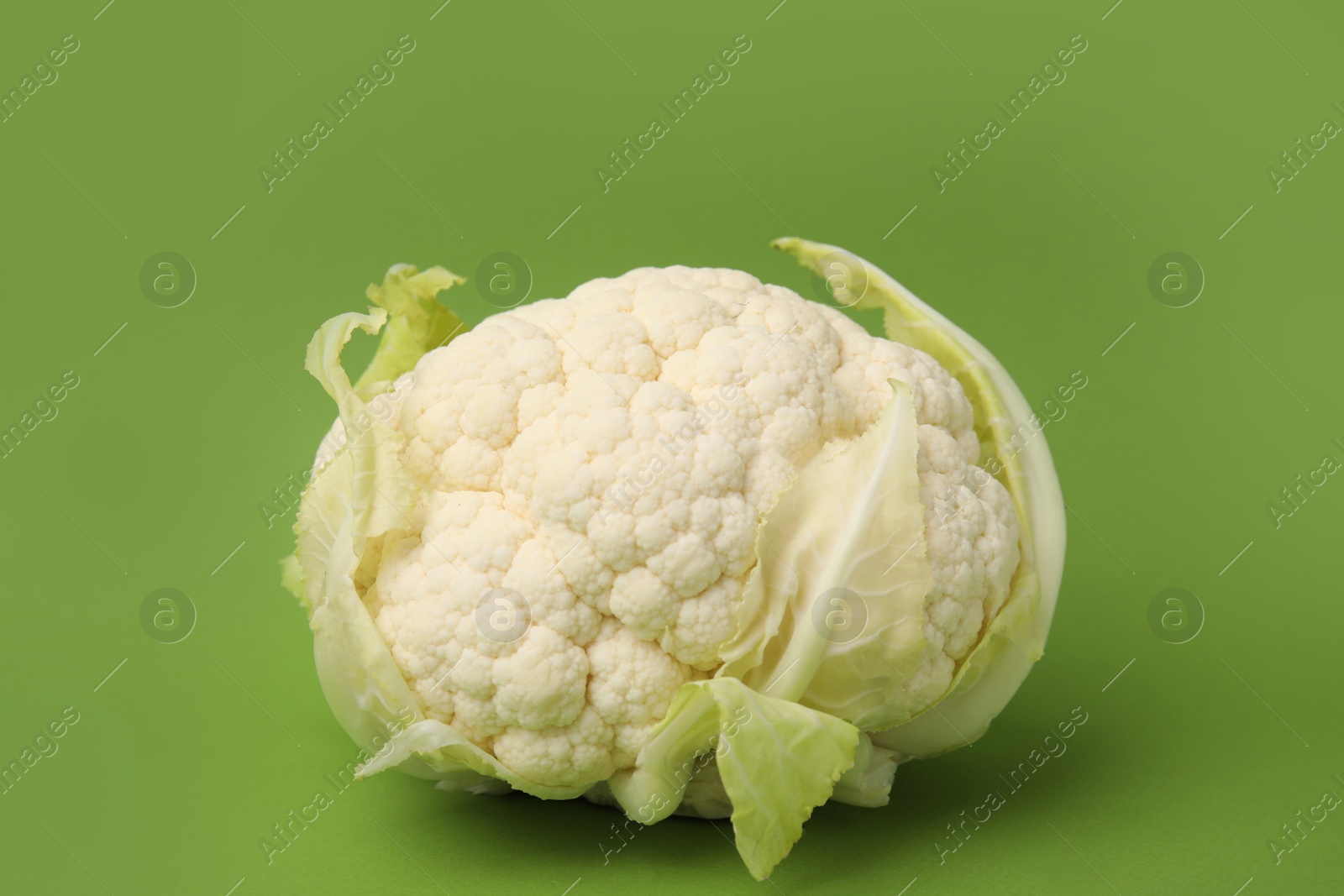 Photo of Whole fresh raw cauliflower on green background