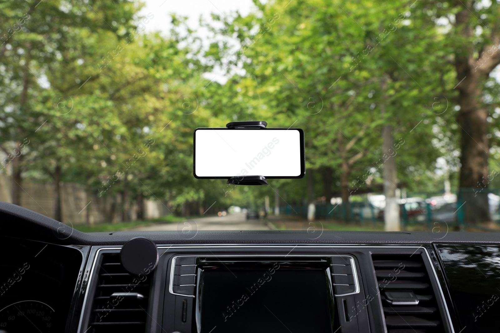 Photo of Car holder with modern mobile phone on windshield of automobile. Mockup for design