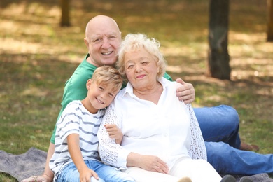 Happy elderly couple with grandson in park