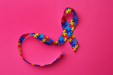 Image of World Autism Awareness Day. Colorful puzzle ribbon on pink background, top view