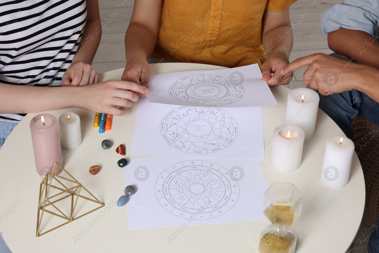 Photo of Astrologer showing zodiac wheel to clients at table, closeup