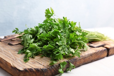 Wooden board with fresh green parsley on table