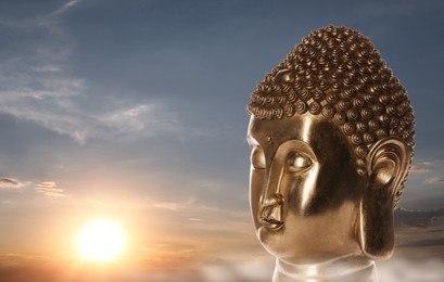 Golden Buddha sculpture and beautfiful sky at sunset on background