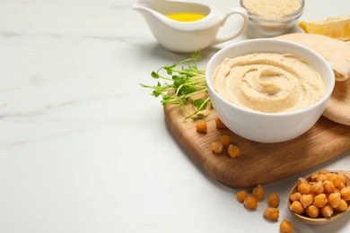 Photo of Delicious hummus and different ingredients on white marble table. Space for text