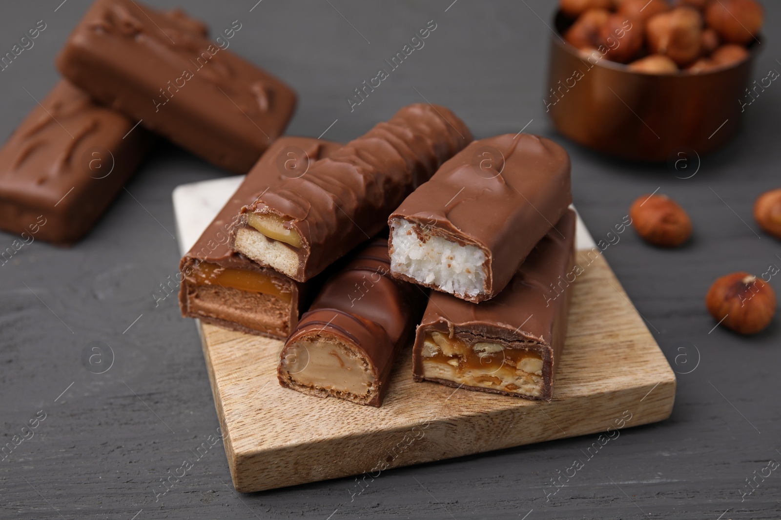 Photo of Pieces of different tasty chocolate bars on grey wooden table, closeup