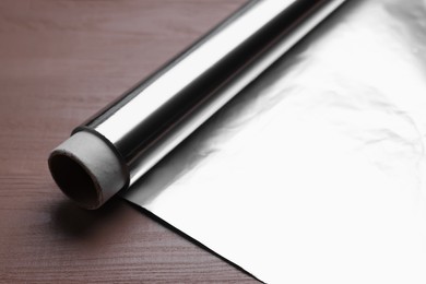 Photo of Roll of aluminum foil on wooden table, closeup