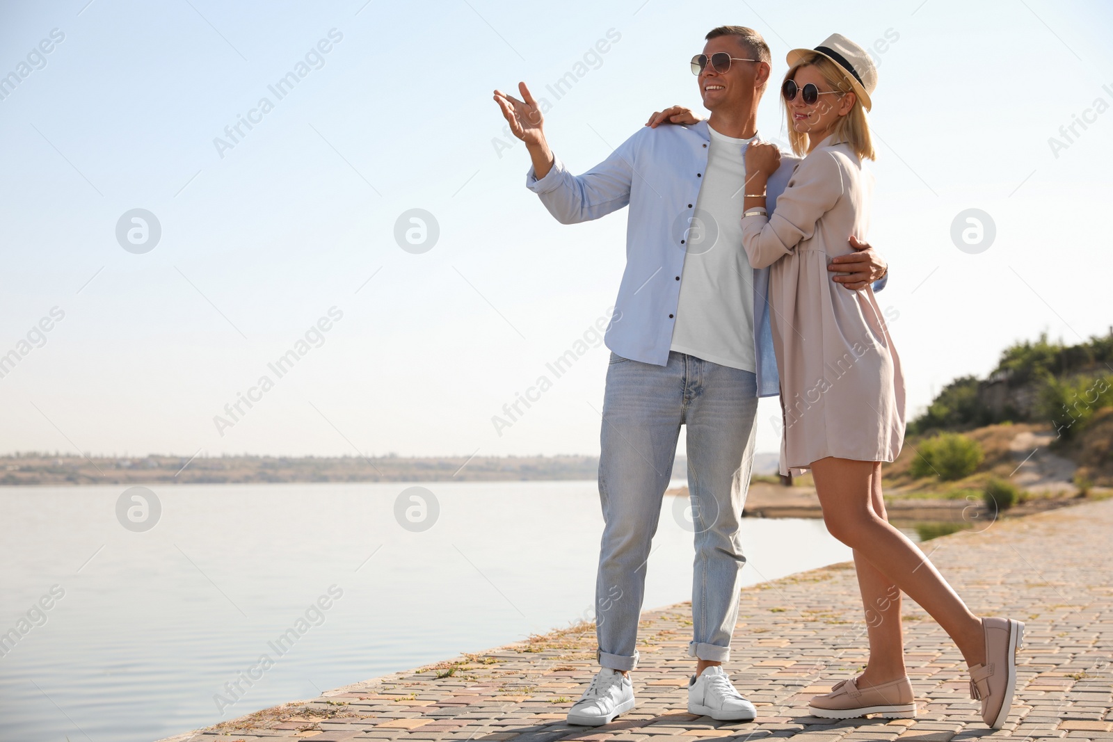 Photo of Happy couple walking along waterfront on summer day