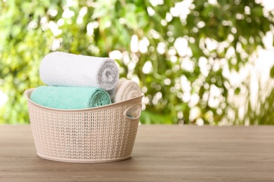 Photo of Basket with clean towels on table against blurred background. Space for text