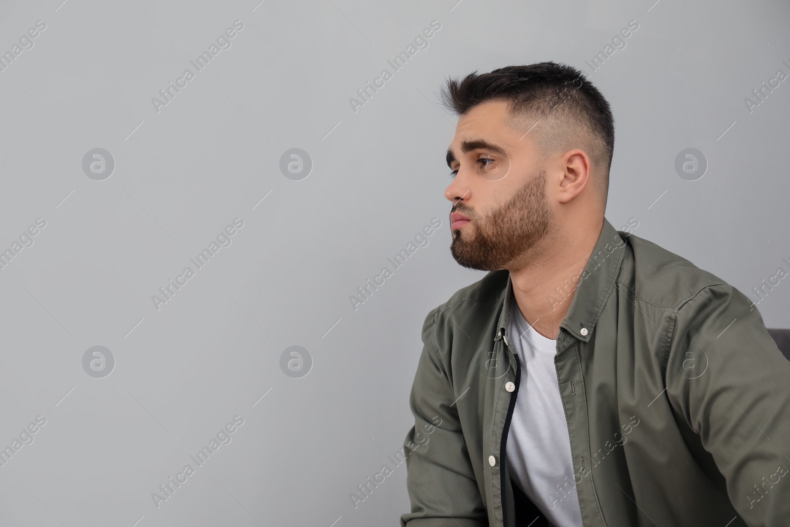 Photo of Portrait of sad man near light grey wall. Space for text