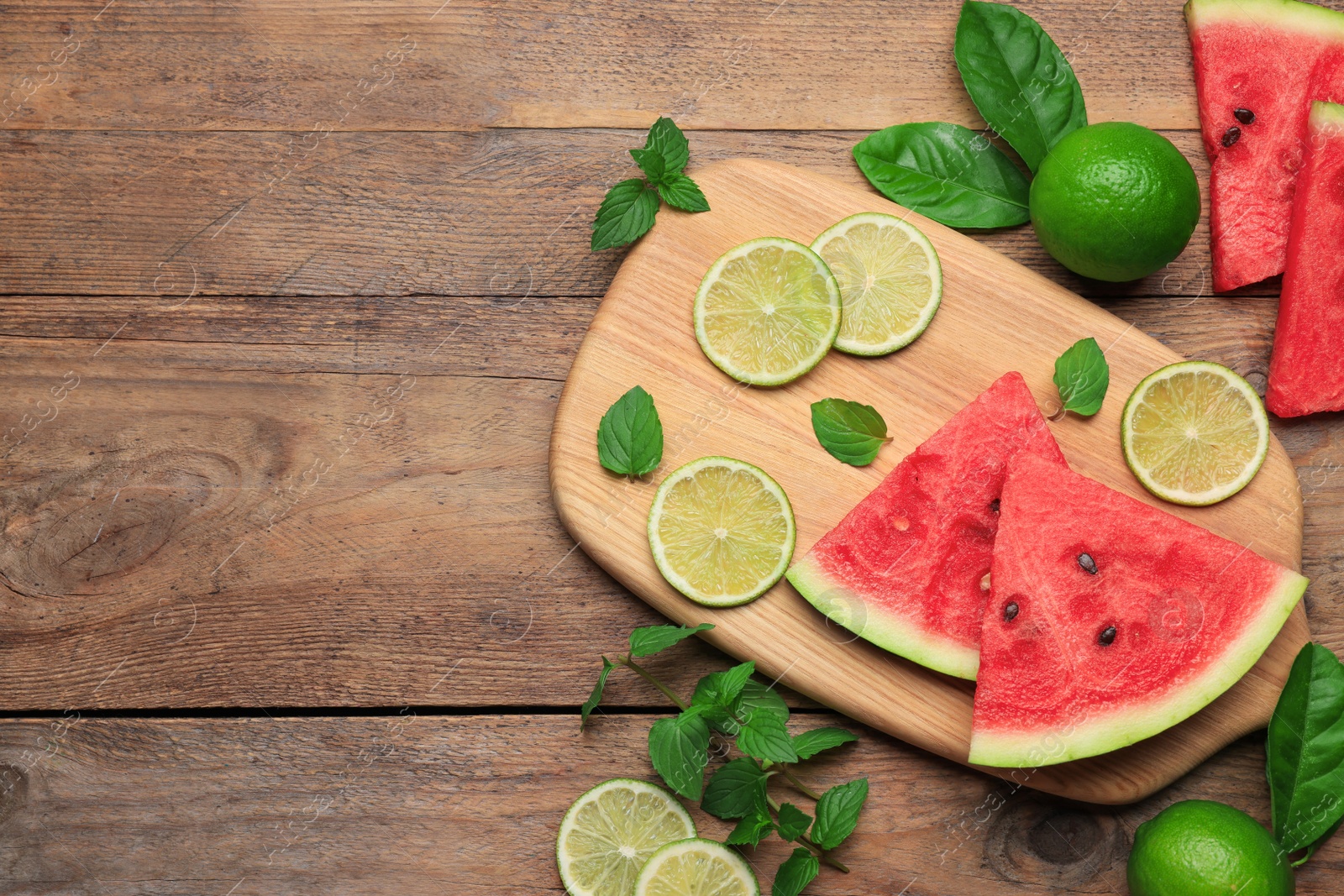 Photo of Tasty sliced watermelon and limes on wooden table, flat lay. Space for text