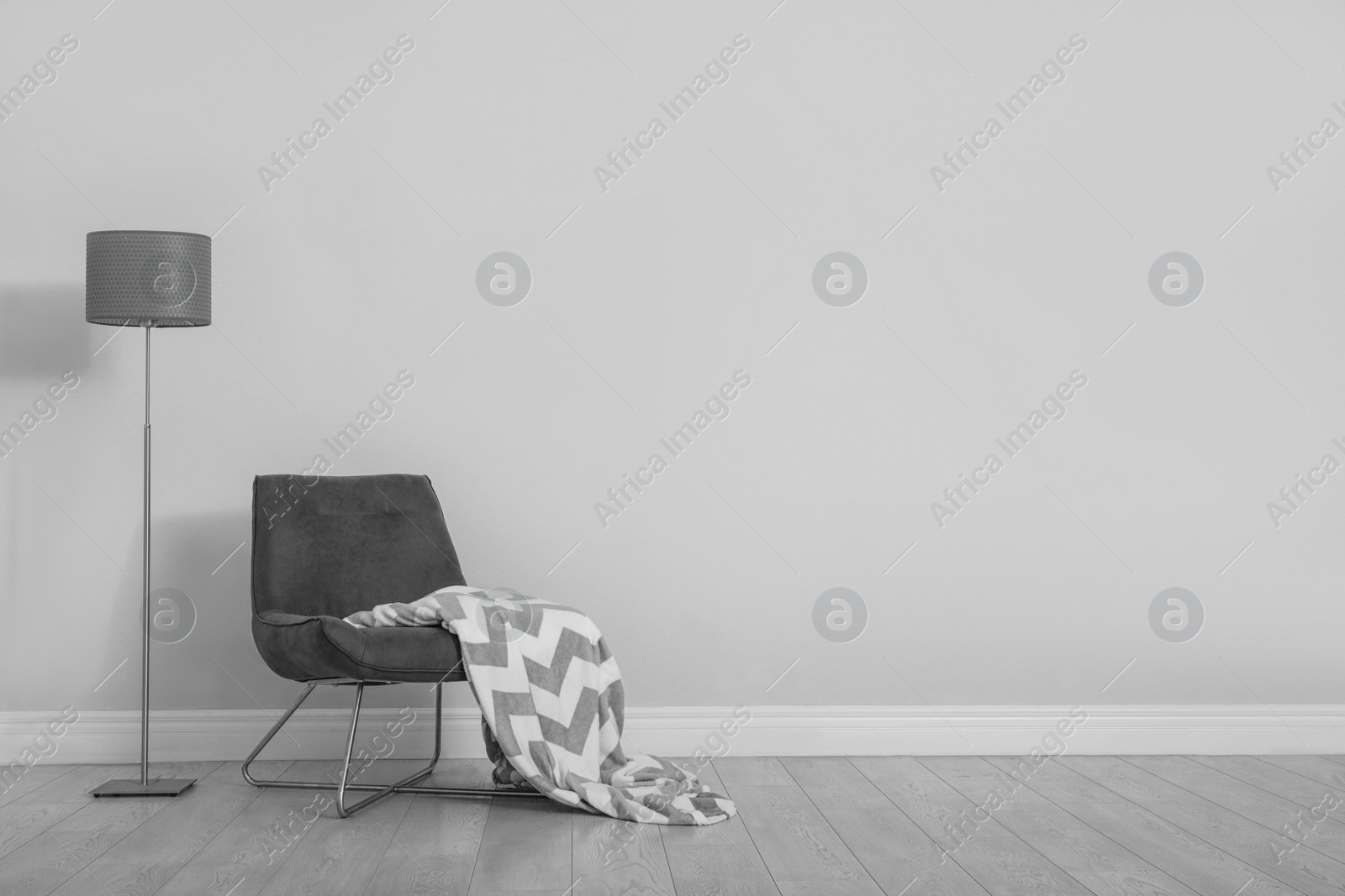 Photo of Stylish room interior with comfortable chair and floor lamp near white wall. Space for text