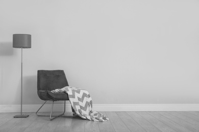 Photo of Stylish room interior with comfortable chair and floor lamp near white wall. Space for text