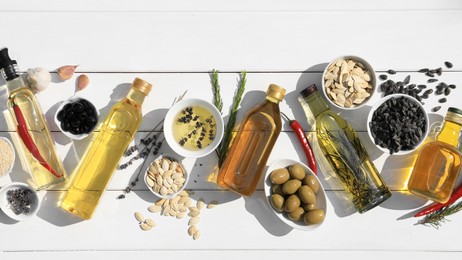 Flat lay composition with different cooking oils and ingredients on white wooden table