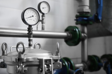 Pressure gauges and pipes indoors, space for text. Production machinery at modern granary