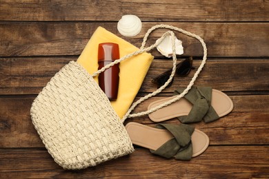 Stylish bag and beach accessories on wooden background, flat lay