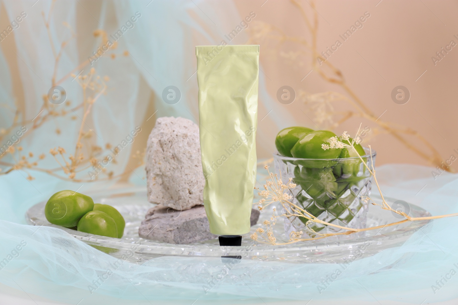 Photo of Tube of cream, olives and stones in glass tray