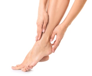 Photo of Young woman applying body scrub on feet against white background