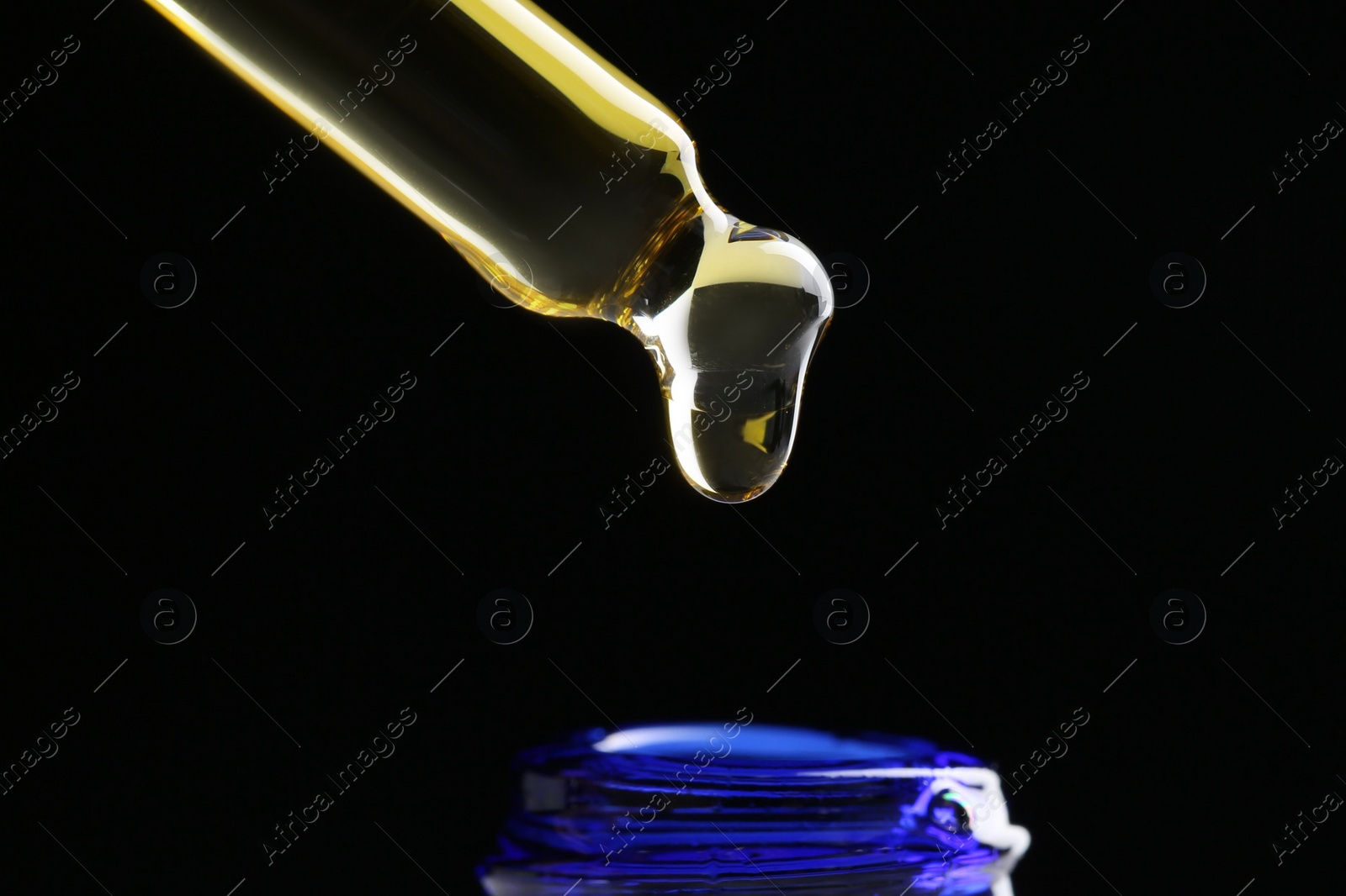 Photo of Dripping tincture from pipette into bottle on black background, closeup