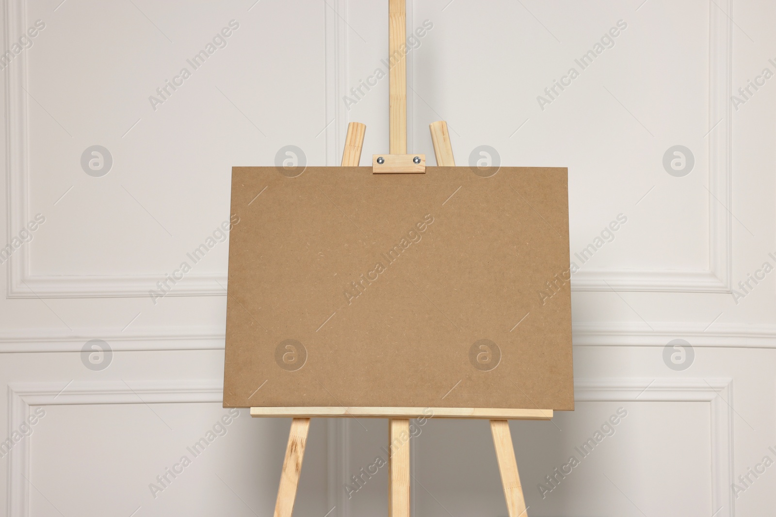 Photo of Wooden easel with blank board near white wall