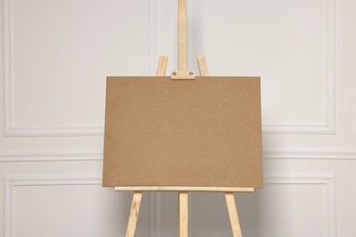 Photo of Wooden easel with blank board near white wall