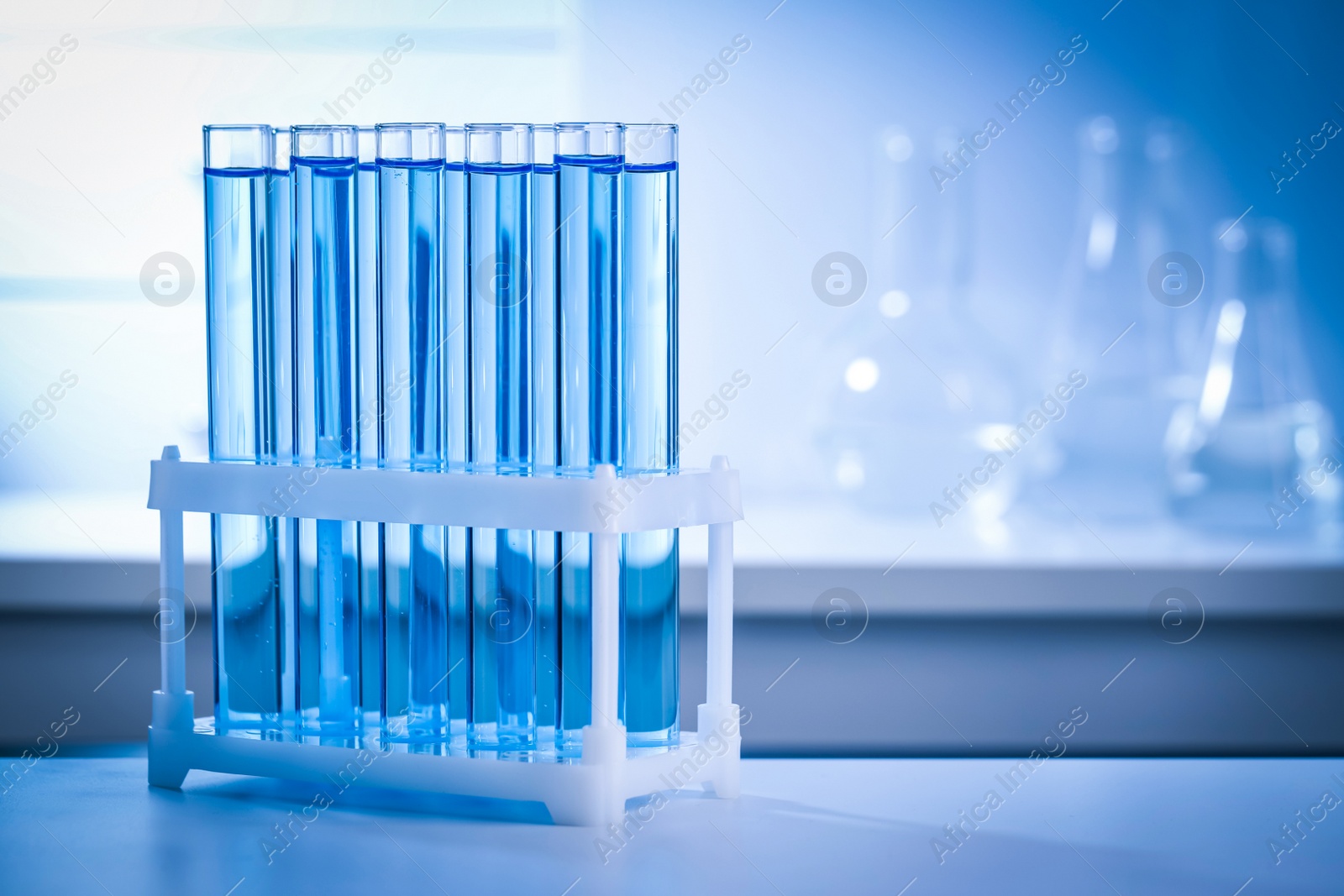 Photo of Test tubes with reagents on table in laboratory, space for text