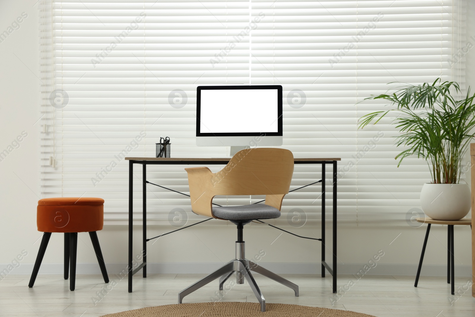 Photo of Stylish office interior with comfortable chair, desk, computer and houseplant