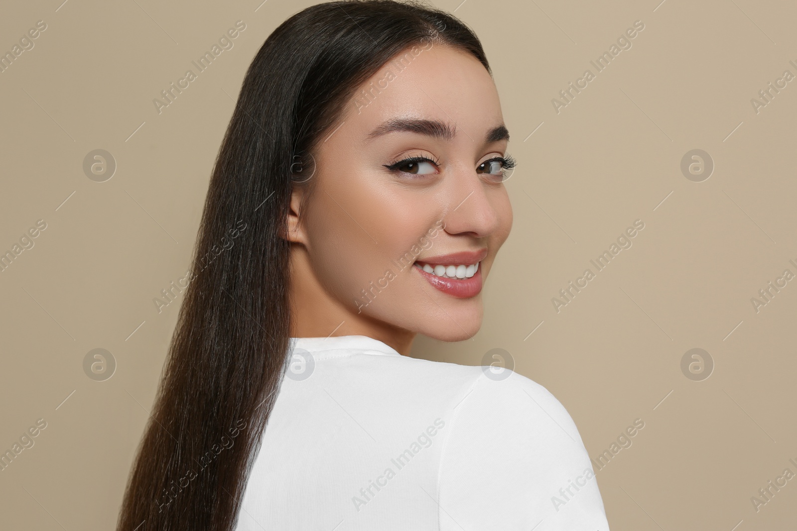 Photo of Portrait of beautiful young woman with elegant makeup on dark beige background