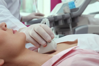 Photo of Doctor conducting ultrasound examination of thyroid gland in clinic, closeup