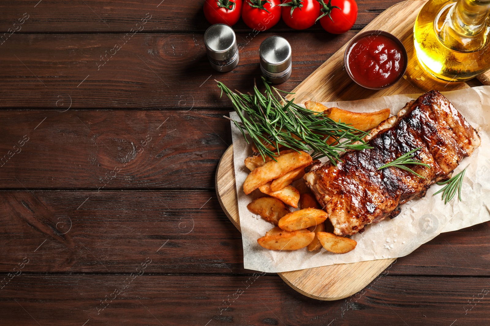 Photo of Delicious grilled ribs and garnish on wooden table, flat lay. Space for text