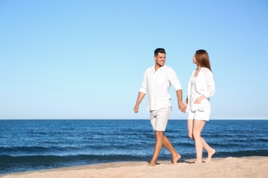 Photo of Lovely couple walking on beach. Space for text