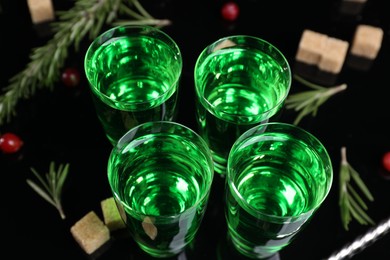 Photo of Absinthe in shot glasses on mirror table, closeup. Alcoholic drink
