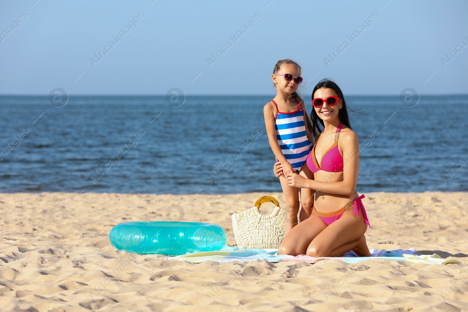 Photo of Happy mother and daughter on sandy beach near sea, space for text. Summer holidays with family